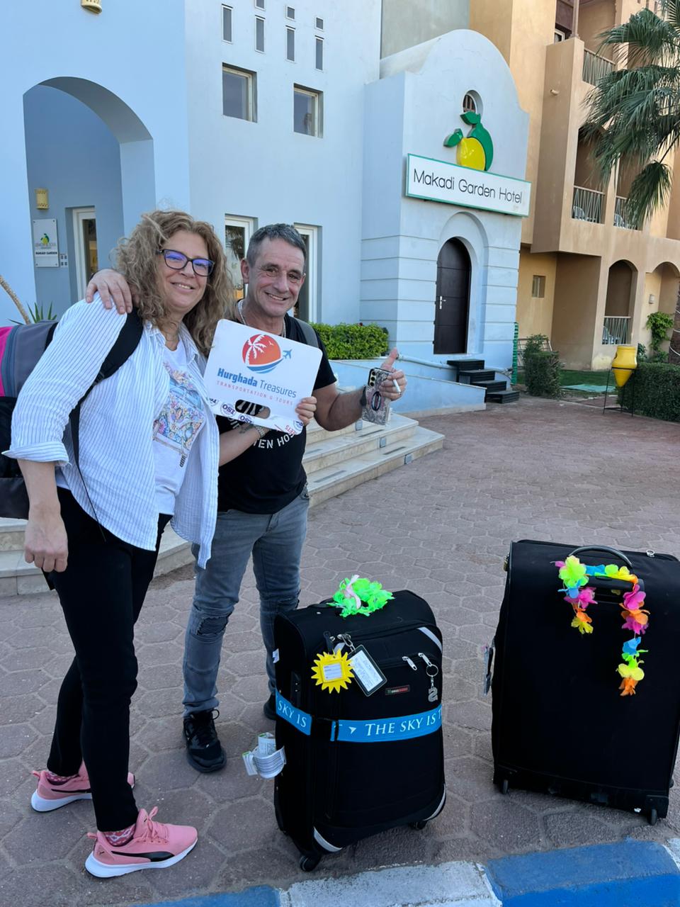Couple with luggage at Makadi Garden Hotel ready for their airport transfer