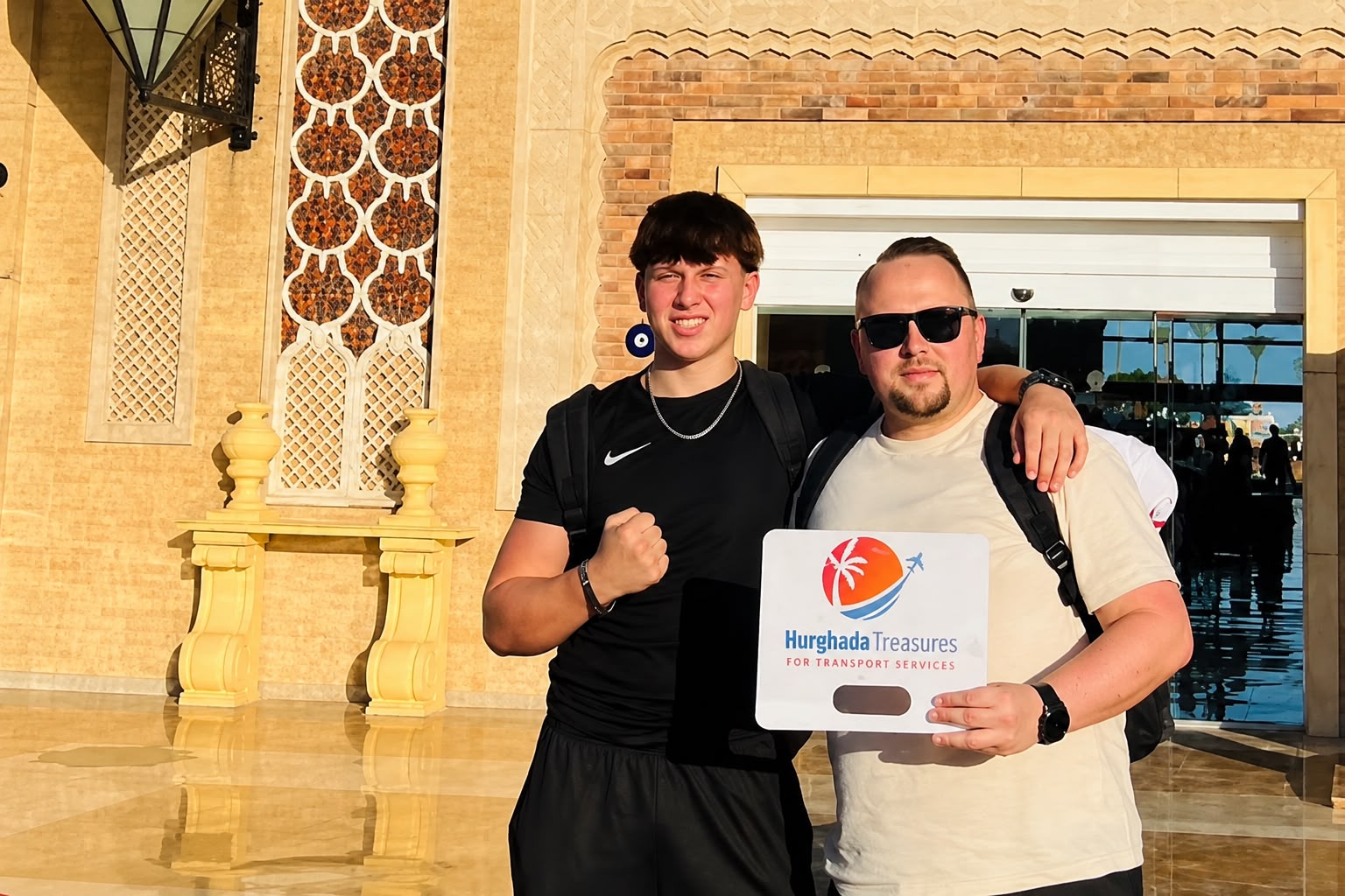 Two guests holding the Hurghada Treasures sign after their private city transfer in Hurghada