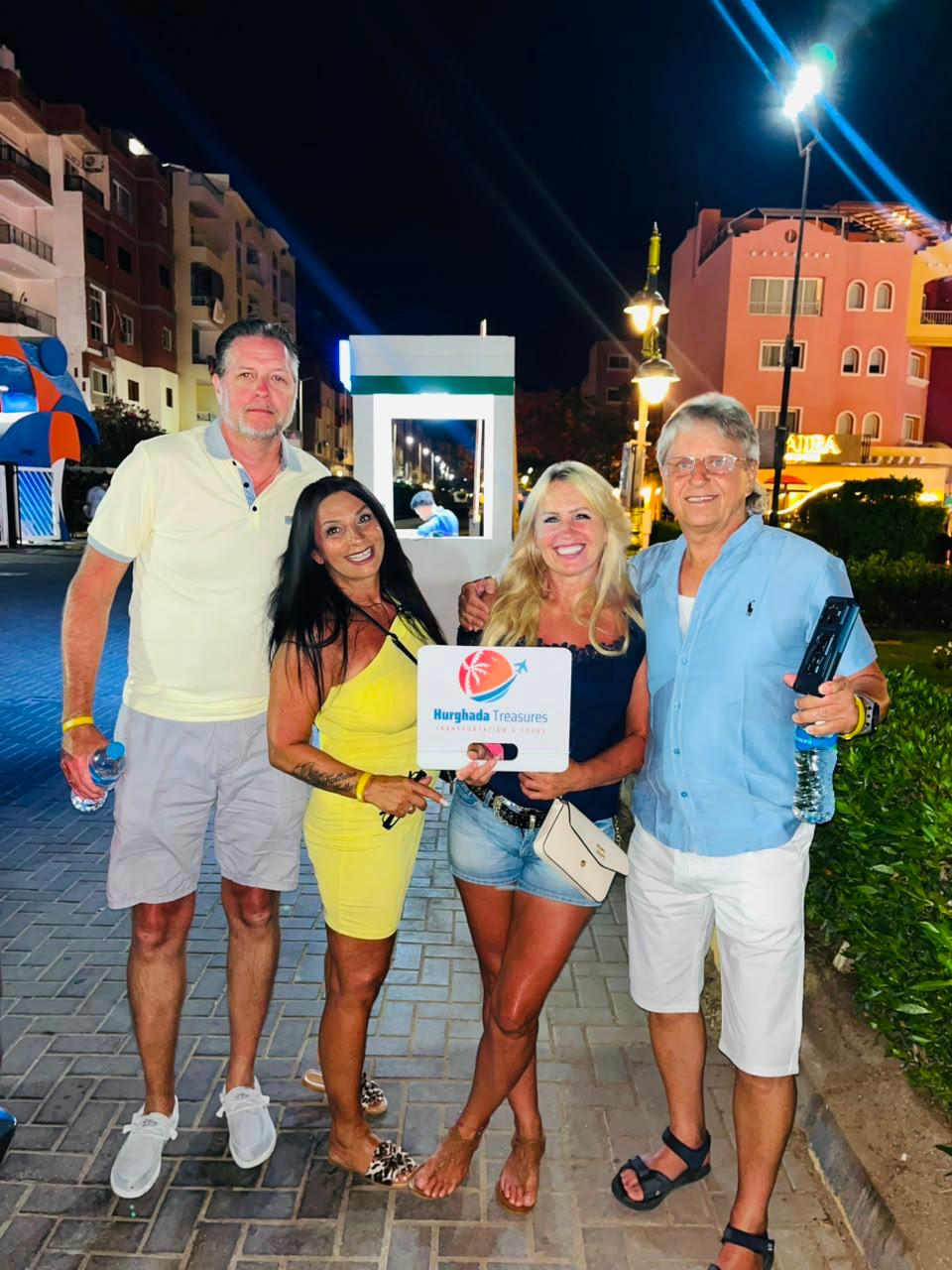 Four guests in downtown Hurghada at night with the Hurghada Treasures sign