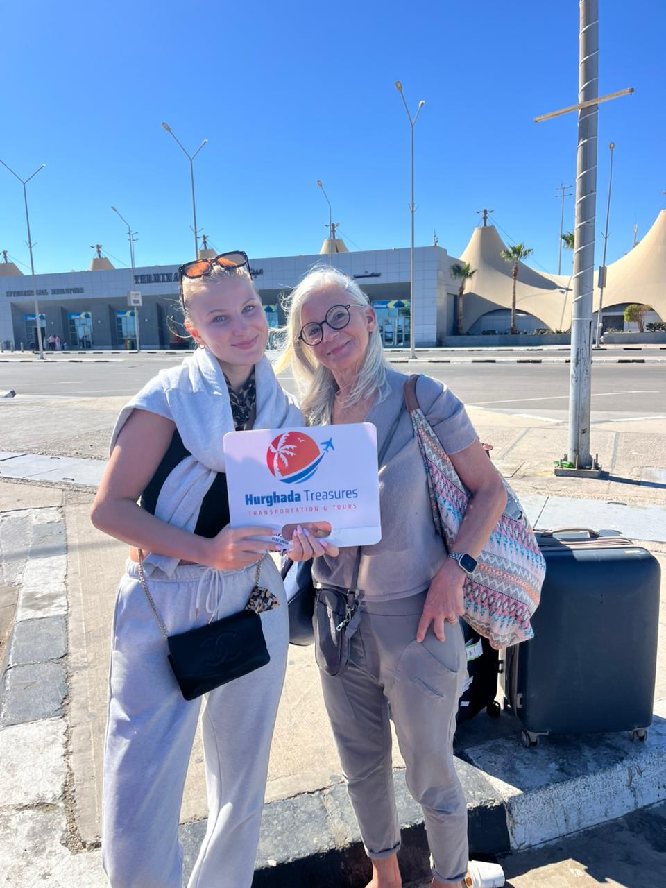 Two guests welcomed with the Hurghada Treasures sign at Hurghada International Airport